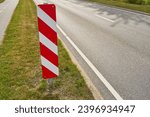 Red and white striped traffic sign on road as safety warning in summer