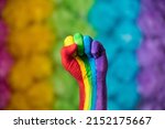 Rainbow colors painted hand raised making fist, sign. Rainbow colors background. LGBT pride symbol. 