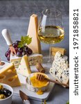 Small photo of topview on cheese plate on marble board for Shavuot with cheese, olives. parmesan, grapes, blueberries. Roquefort cheese. brie and glass of white wine. honey and brie