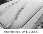 Small photo of The windshield wiper blades are frozen to the car windshield. Snowy windshield with wipers on a cold winter morning. The concept of operating a car in winter.