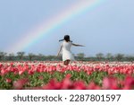 A girl playing in a flower garden with a rainbow