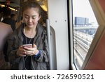 Asian cute woman passenger  using and listening the song via smart mobile phone in the Sky train rails or subway for travel in the big city, lifestyle and transportation concept.BTS