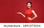 Small photo of Happy Chinese new year. Asian woman wearing traditional cheongsam qipao dress with gesture of introduce isolated on red background.