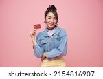 Small photo of Happy beautiful Asian teen shopaholic women showing credit card isolated on pink background.