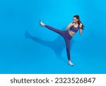 Small photo of Asian female athlete workout, practice leg kicks, kicking air in sportswear. Muscular trained woman kicking with raised feet, exercise kickboxing moves, blue background.