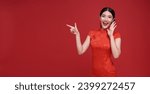 Small photo of Happy Asian woman wearing red dress shouting announce and hands pointing finger to copy space isolated on red background.