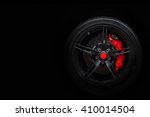 Isolated generic sport car wheel with red breaks and dark rim on a black background