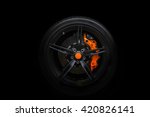 Isolated generic sport car wheel with orange breaks a black background