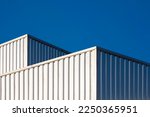 Two Corrugated steel Industrial Buildings with sunlight reflection on surface against blue clear sky background