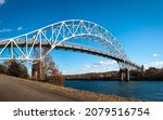 Sagamore Bridge connecting Cape Cod Canal riverbanks. Arching steel bridge on blue sky and river water background in autumn. Beautiful Bourne landscape on Cape Cod, Massachusetts.