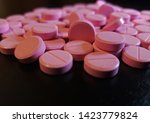 Small photo of Pink Nitroglycerin Pills scattered on glossy black background - 001