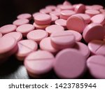 Small photo of Pink Nitroglycerin pills scattered on glossy black background - 009