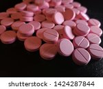 Small photo of Pink Nitroglycerin pills scattered on glossy black background - 006