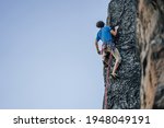 A climber on a steep rock. Rock climbing, extreme adrenaline sport climbing. Ascending a rock wall to the top.