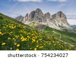 Beautiful summer mountain view of Passo Sella and high peak Sassopiatto and Sassolungo, Langkofel, Dolomiti, Sella group. Green meadows and pastures, alpine dolomites peaks and blue sky.