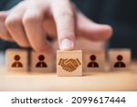 Hand putting hand shaking which print screen on wooden cube block  in front of human icon for business deal and agreement concept.