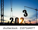 Small photo of Silhouette of construction worker with crane and cloudy sky for preparation of welcome 2023 new year party and change new business.