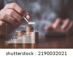 Businessman drawing increasing graph with coin stacking for increase financial interest rate and business investment growth from dividend concept.
