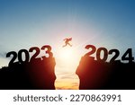 Welcome merry Christmas and happy new year in 2024,Silhouette Man jumping from 2023cliff to 2024 cliff with cloud sky and sunlight.