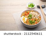 Instant noodle soup with minced pork and boiled egg in white bowl on wood table.with copy space