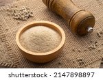 ground white pepper in wooden bowl on wood table