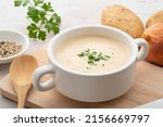 Bowl of creamy potato soup on wooden plate