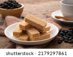 Small photo of Wafer with coffee flavored cream in white plate with cup and coffee bean background