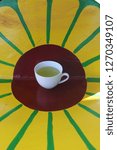 Small photo of White hot cup of tea on the table in the shape of an yellow orange.