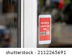 Small photo of Milwaukie, OR, USA - June 18, 2021: Closeup of the Yelp sticker seen at the entrance to a restaurant in Milwaukie, Oregon. Yelp operates an online platform that connects people with local businesses.
