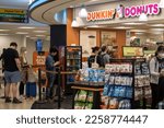 Small photo of New York, NY, USA - July 9, 2022: Passengers wait in line at a Dunkin' Donuts shop in the terminal building of the John F. Kennedy International Airport.