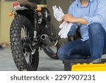 Mechanic working in motorcycle repair shop, wearing protective gloves. Bike Maintenance Concept.
