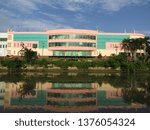 Small photo of Surabaya, Indonesia - April 21 2019: View of the back of JMP Grocery Mall Market Building with clear blue sky clouds and river background with trees around. Nearby with Red Bridge Historical Duct area