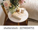 Still life details in home interior of living room. Open book with glasses, cup coffee and bouquet white pink peonies flowers. Read and rest. Cozy home