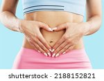Small photo of Young healthy woman hand made heart shape on her stomach. Concept of good digestive, healthy gut, probiotics, slim fit, gynecology and woman health care.