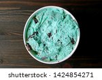 Top View of Mint Chocolate Chip Ice Cream in a Large Cup on Dark Brown Wooden Table