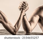 Small photo of Arm wrestling. Heavily muscled bearded man arm wrestling a puny weak man.