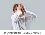 Small photo of Little boy having a headache. Despair, tragedy. Headache child. Suffering migraine. Headache because stress. Portrait of a sad boy holding his head with his hand, isolated on the gray background.