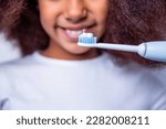 Small photo of Little girl toothbrush closeup. Little cute african american girl brushing her teeth. Healthy teeth. Small afro girl, toothbrush. Multiracial girl brushes her teeth an electric toothbrush close-up.