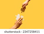 Small photo of Hand connecting jigsaw puzzle. Man hands connecting couple puzzle piece. Closeup hands of man connecting jigsaw puzzle. Two hands trying to connect couple puzzle with yellow background.