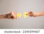 Small photo of Mens and childs hands connecting puzzles. Hands connecting puzzle. Puzzles. Hand of the child and hand of mother fold puzzle, closeup. Hands hold puzzles. Solution of problems.