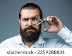 Small photo of Barber scissors. Vintage barbershop, shaving. Male in barbershop, haircut, shaving. Bearded man isolated on gray background. Mans haircut in barber shop. Barber scissors, barber shop.