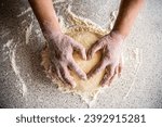 Cooking with love. Female hands holding dough in heart shape. Hands gently touch the raw dough in the form of heart. Female hands holding dough in heart shape.