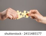 Small photo of Puzzles. Man and woman holds in hand a jigsaw puzzle. Business solutions, success and strategy concept. Hands connecting puzzle. Hand of the man and hand of woman fold puzzle, closeup.