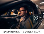 Side view portrait of a handsome stylish man driving car at night