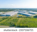 Small photo of Aerial view of goods warehouse. Logistics center in industrial city zone from above. Aerial view of trucks loading at logistic center
