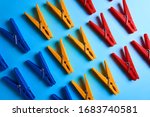 Multi-colored clothespins on a blue background lie in 3 rows.Bright objects.Perfectionism