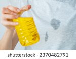 Small photo of Grease stains in a clothes. An unrecognized woman is holding a corn oil. daily life stain concept. High quality photo
