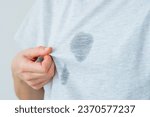 Small photo of Unrecognized surprised female showing at dirty grease stain on a gray t-shirt. daily life stain concept. High quality photo