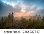 Sunset behind clouds with low hanging clouds over forest looks like forest fire in distance