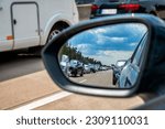 Looking in the rearview mirror at an emergency lane in a long traffic jam